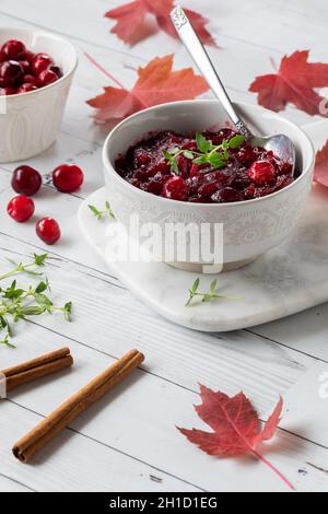 Vertikale Ansicht einer Schüssel mit hausgemachter Preiselbeersauce, garniert mit Thymian. Stockfoto