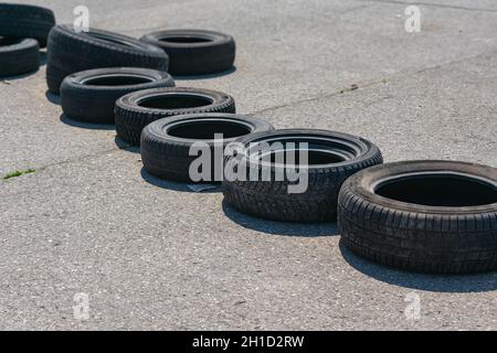 Alte Autoreifen liegen in Form einer Blockade auf der Rennstrecke auf dem Asphalt Stockfoto