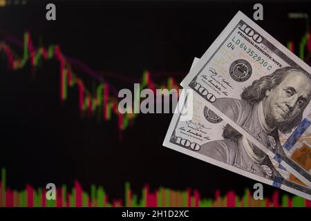 Hände, die Dollar vor einem Laptop-Monitor mit einem Kursdiagramm halten.Forex und trading.A Händler handeln Aktien, Anleihen und Wertpapiere oder Währungen auf t Stockfoto