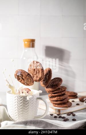 Frische Schokoladenkekse, die in einer Tasse Milch spritzen Stockfoto