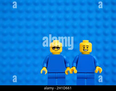 Tambow, Russische Föderation - 17. Oktober 2021 zwei Lego Minifiguren - eine in Sonnenbrille und eine mit einem Grinsen vor blauem Hintergrund. Studioaufnahme. Stockfoto