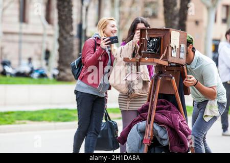 BARCELONA - MÄRZ 2018: Junger männlicher Fotograf, der mit einer alten Holzkamera am Triumphbogen in Barcelona fotografiert Stockfoto