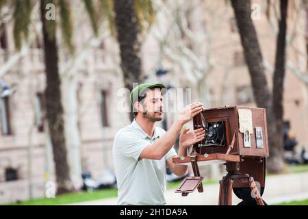 BARCELONA - MÄRZ 2018: Junger männlicher Fotograf, der mit einer alten Holzkamera am Triumphbogen in Barcelona fotografiert Stockfoto