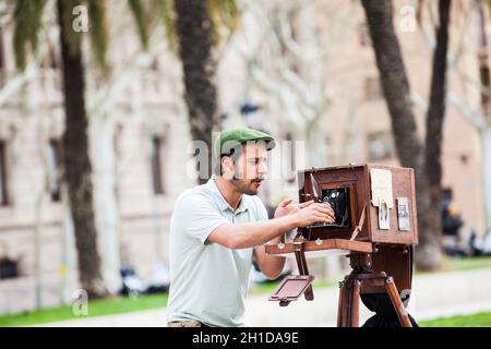 BARCELONA - MÄRZ 2018: Junger männlicher Fotograf, der mit einer alten Holzkamera am Triumphbogen in Barcelona fotografiert Stockfoto