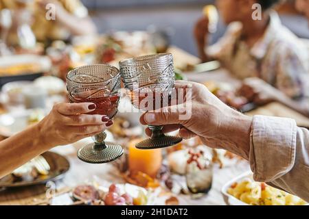 Nahaufnahme eines älteren Ehepaares, das mit Gläsern mit Rotwein röste, während er mit der Familie am Esstisch saß Stockfoto