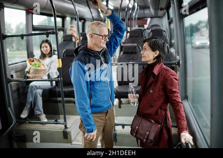 Seitenansicht Porträt von zwei Erwachsenen, die sich im Bus unterhalten und mit öffentlichen Verkehrsmitteln in der Stadt unterwegs sind, Kopierraum Stockfoto