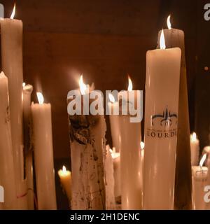 Lourdes, Frankreich - 9 Oct 2021: Kerzen leuchten an einem Heiligtum in der Rosenkranzbasilika von Lourdes, einem katholischen Wallfahrtsort Stockfoto