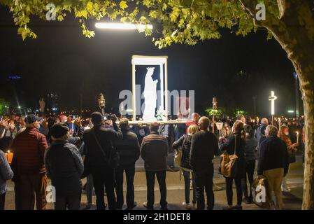 Lourdes, Frankreich - 9. Oktober 2021: Während der Marian Facklight Prozession in der Rosenkranzbasilika i wird eine Statue der Jungfrau Maria in die Menge getragen Stockfoto
