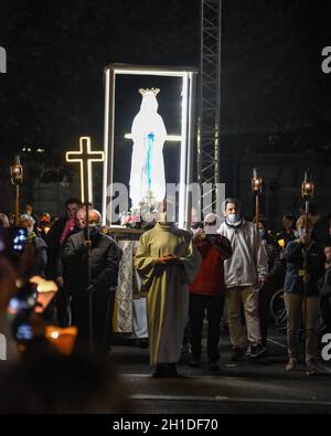 Lourdes, Frankreich - 9. Oktober 2021: Während der Marian Facklight Prozession in der Rosenkranzbasilika i wird eine Statue der Jungfrau Maria in die Menge getragen Stockfoto
