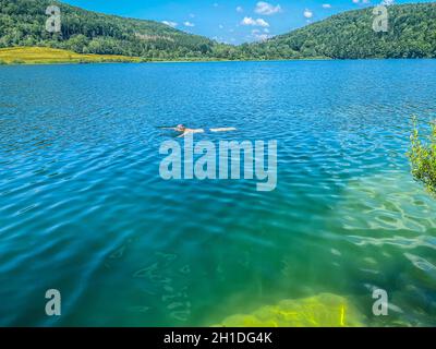 Eine nicht erkennbare Person schwimmt im Narlay-See, Le Frasnois, Bourgogne-Franche-Comté, Jura Stockfoto