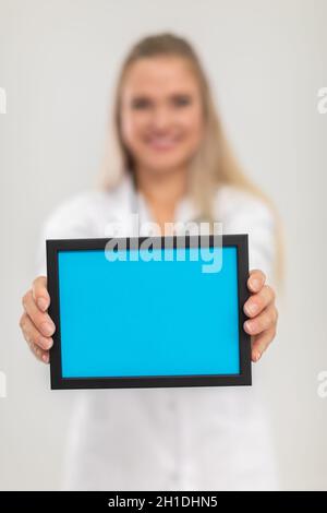 Im Vordergrund ist eine rechteckige blaue Plakette und im Hintergrund sieht man eine Ärztin. Stockfoto