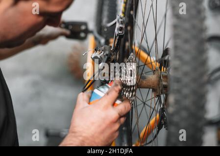 Mechaniker mann Hand, spritzen Öl in ein Fahrrad Kette. Fahrrad Wartung. Stockfoto