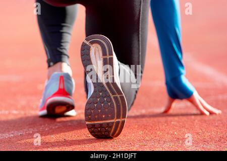 Rückansicht eines Athleten erhalten für das Rennen auf einem laufenden Track bereit. Fokus auf Schuh eines Athleten zu einem Rennen im Stadion. Stockfoto