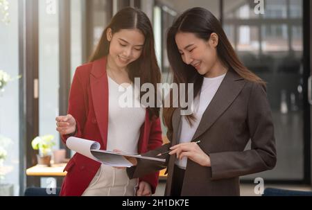 Zwei asiatische weibliche Kollegen stehen nebeneinander in einem Büro, Business Meeting Diskussionskonzept Stockfoto