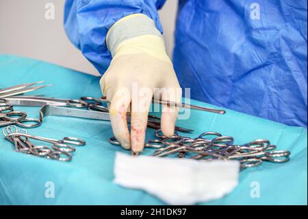 Nahaufnahme der Pflegekraft, die medizinische Instrumente für den Betrieb mit Kollegen im Hintergrund mitnimmt. Stockfoto