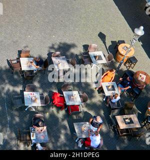 Braunschweig, 14. August 2021: Blick von oben auf Tische, Stühle und Gäste eines Straßenrestaurants auf dem Bürgersteig, mit Kopierfläche Stockfoto