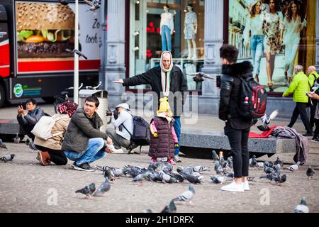 AMSTERDAM, NIEDERLANDE - MÄRZ 2018: Menschen füttern Tauben in den Dam Platz im alten Zentrum von Amsterdam. Stockfoto