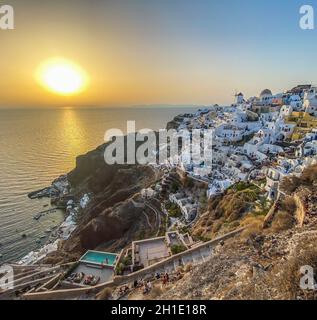 Panoramablick auf das Dorf Oia mit traditioneller weißer Architektur und Windmühlen auf der Insel Santorini in der Ägäis bei Sonnenuntergang, Reisehintergrund, Santor Stockfoto