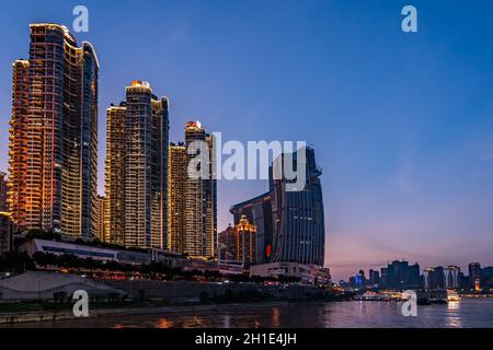 Chongqing, China - August 2019 : Nachtsicht auf die modernen Geschäfts- und Geschäftsgebäude am Flussufer bei Dämmerung Stockfoto