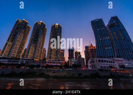 Chongqing, China - August 2019 : Nachtsicht auf die modernen Geschäfts- und Geschäftsgebäude am Flussufer bei Dämmerung Stockfoto