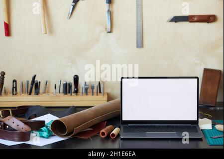 Hintergrundbild eines Laptops mit leerem weißen Bildschirm in der Gerber-Werkstatt, Konzept für kleine Unternehmen, Kopierplatz Stockfoto