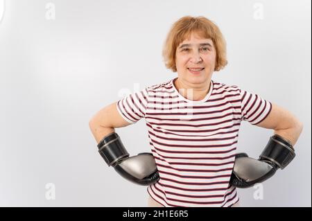 Ältere Frau in Kampfhandschuhen in einer defensiven Pose auf weißem Hintergrund. Stockfoto