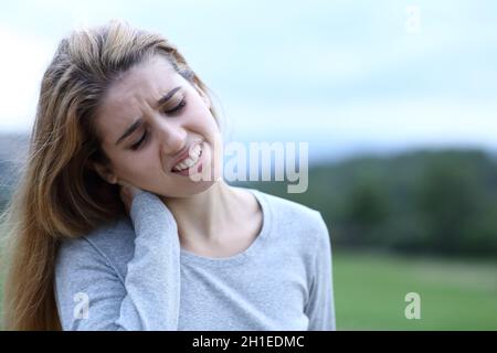 Teenager, der sich auf einem Feld über Nackenschmerzen beschwert Stockfoto