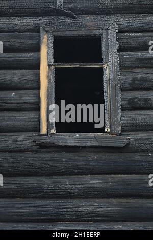 Holzhaus nach dem Feuer. Kohlen auf den Protokollen. Die Asche des Hauses aus dem Feuer. Verbrannte zerstörte Hütte. Stockfoto