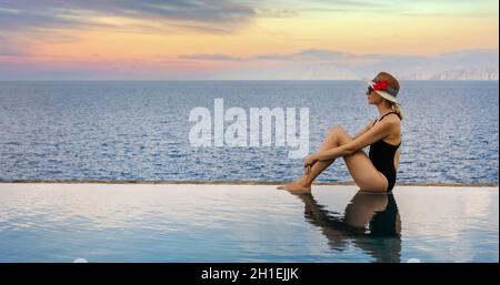 Frau, die sich am Rande des unendlichen Swimmingpools im Luxus-Resort entspannt. Sommerurlaub. Banner-Kopierraum Stockfoto