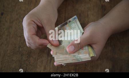 salvador, bahia / brasilien - 28. märz 2020: Frauenhände halten die in Brasilien verwendeten Reais-Banknoten. Stockfoto