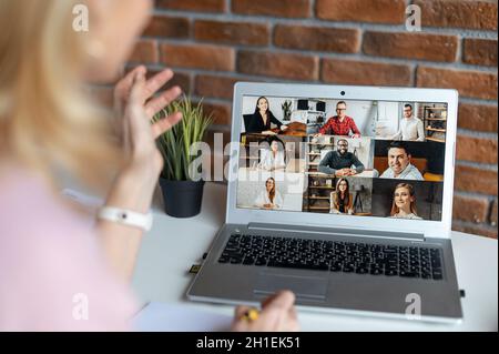 Nahaufnahme einer Frau, die eine App für die Videokommunikation über Entfernungen mit Kollegen, Freunden, Online-Meetings und den Blick auf den Laptop-Desktop mit den Personen-Profilen verwendet, Webinar-Teilnehmer. Weibliche Hände beim Tippen Stockfoto