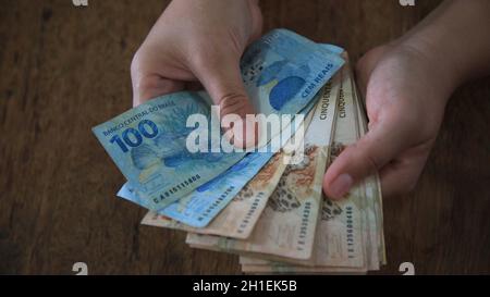 salvador, bahia / brasilien - 28. märz 2020: Frauenhände halten die in Brasilien verwendeten Reais-Banknoten. Stockfoto