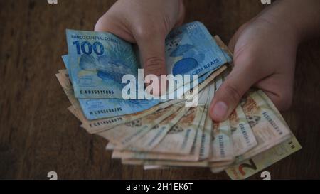 salvador, bahia / brasilien - 28. märz 2020: Frauenhände halten die in Brasilien verwendeten Reais-Banknoten. Stockfoto