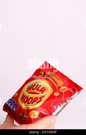 Ungeöffnetes Paket mit Hula Hoops in jungen Händen vor weißem Hintergrund Stockfoto