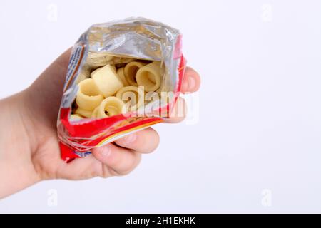 In einer Packung Hula Hoops, die Chips zeigt, in der Hand der Jungen vor weißem Hintergrund Stockfoto
