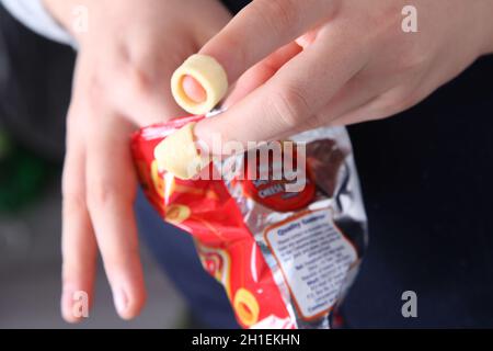 Hula Hoops auf Fingerspitzen mit einer Tüte Chips. Stockfoto