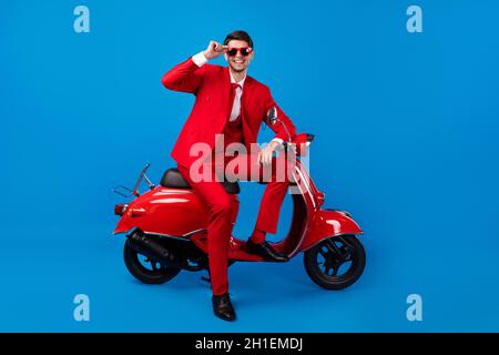 In voller Länge Foto von jungen schönen Kerl glücklich positive Lächeln sitzen Fahrrad cool Sonnenschutzscheibe isoliert über blauen Hintergrund Stockfoto