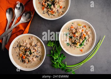 Schalen mit Hühnchen und Wildreis-Suppe: Blick von oben auf cremige Hühnchen- und Wildreissuppe mit Spinat und Karotten Stockfoto
