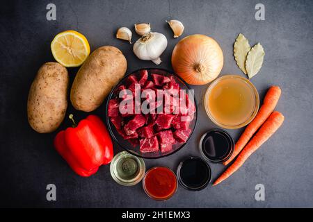 Mechado Filipino Rindereintopf Zutaten auf dunklem Hintergrund: Rohes Rindereintopf mit ungekochten Gemüse, Kräutern und Gewürzen Stockfoto