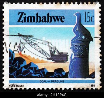 SIMBABWE - UM 1985: Eine in Simbabwe gedruckte Marke zeigt den Vogel- und Kohlebergbau in Simbabwe, die Industrie, um 1985 Stockfoto