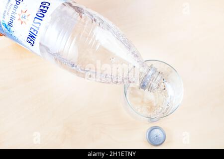 MOSKAU, RUSSLAND - 10. MAI 2020: Gießen von Gerolsteiner-Mineralwasser aus Plastikflaschen in Glas an Bord. Gerolsteiner ist natürlich Deutsche carbona Stockfoto
