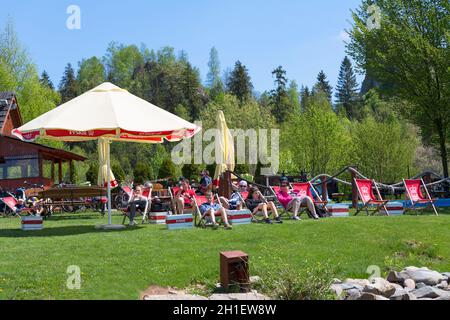 Niedzica; Polen - 18. Mai; 2020: Touristen ruhen sich auf Sonnenliegen am Ufer des Czorsztyn-Sees neben dem Yachthafen für Touristenschiffe aus Stockfoto