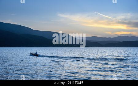 Ein Fischer bei Sonnenuntergang am Mikri Prespa See im Dorf Mikrolimni in Mazedonien, Nordgriechenland. Stockfoto