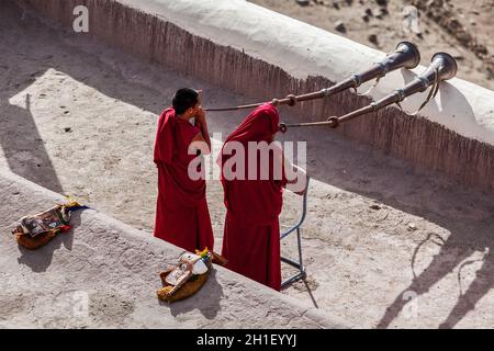 THIKSEY, INDIEN - 4. SEPTEMBER 2011: Zwei tibetisch-buddhistische Mönche blasen während des morgendlichen Pooja, Thiksey gompa, Ladakh, Indien, Tibetanisches Horn (Dungche) Stockfoto