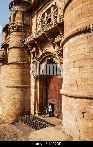 GWALIOR, INDIEN - 11. APRIL 2011: Mann mit Fahrrad kommt durch die Tür in riesigen Toren von Gwalior Fort - 8. Jahrhundert Hügel Festung, die viele historische Häuser Stockfoto