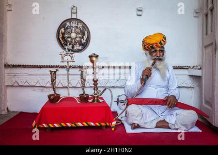 JODHPUR, INDIEN - 26. NOVEMBER 2012: Alter Inder raucht Shisha (Wasserpfeife) in der Festung Mehrangarh. Das Konzept der Shisha wird angenommen, dass ich entstanden ist Stockfoto