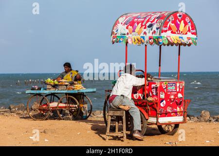 PONDICHERRY, INDIEN - 2. FEBRUAR 2013: Nicht identifizierte indische Straßenverkäufer von Eis und Snacks mit Rollwagen am Strand Stockfoto