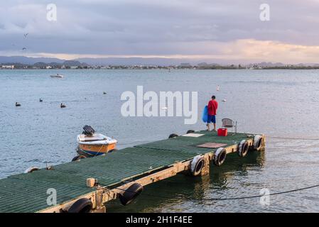 San Juan, Puerto Rico - 30. April 2019: Ein eingefelschiger Fischer steht auf einem Pier mit einem Fischernetz während des Sonnenuntergangs in San Juan, Puerto Rico, Karibik. Stockfoto