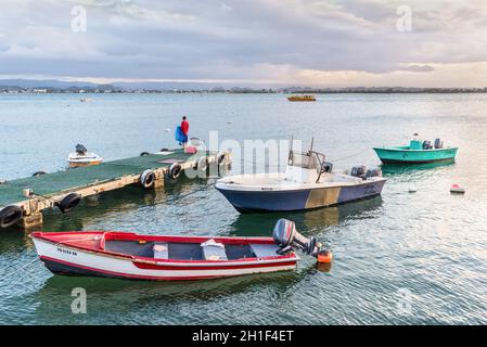 San Juan, Puerto Rico - 30. April 2019: Fischerboote vor dem Hafen von San Juan, Puerto Rico, Karibik. Ein einiger Fischer steht auf einem Pier mit Witz Stockfoto