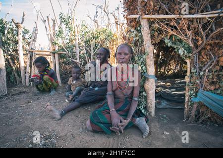 Omorate, Omo Valley, Äthiopien - 11. Mai 2019: Frau aus dem afrikanischen Stamm Dasanesh mit Kindern vor seiner Hütte. Daasanach sind cushitic ethnischen g Stockfoto